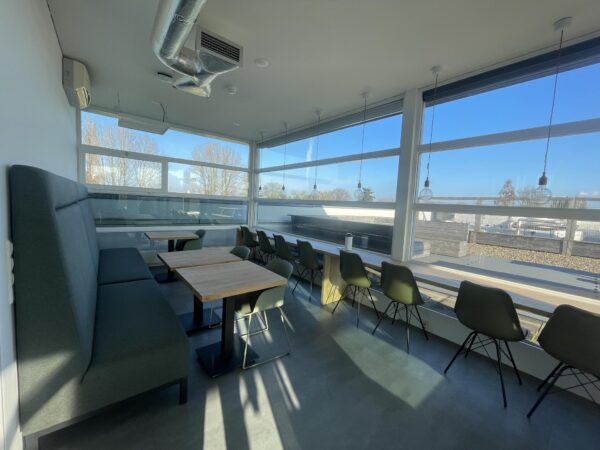 Moderne en lichte bedrijfsruimte aan de Jan Leentvaarlaan met zitplaatsen langs het raam en een lange bank.